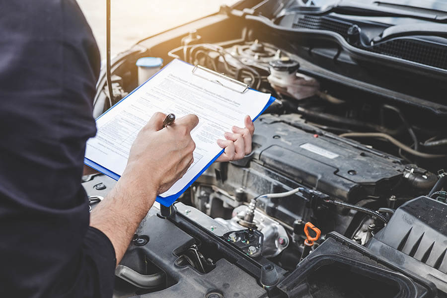 auto repair mechanic using a checklist to inspect a car engine